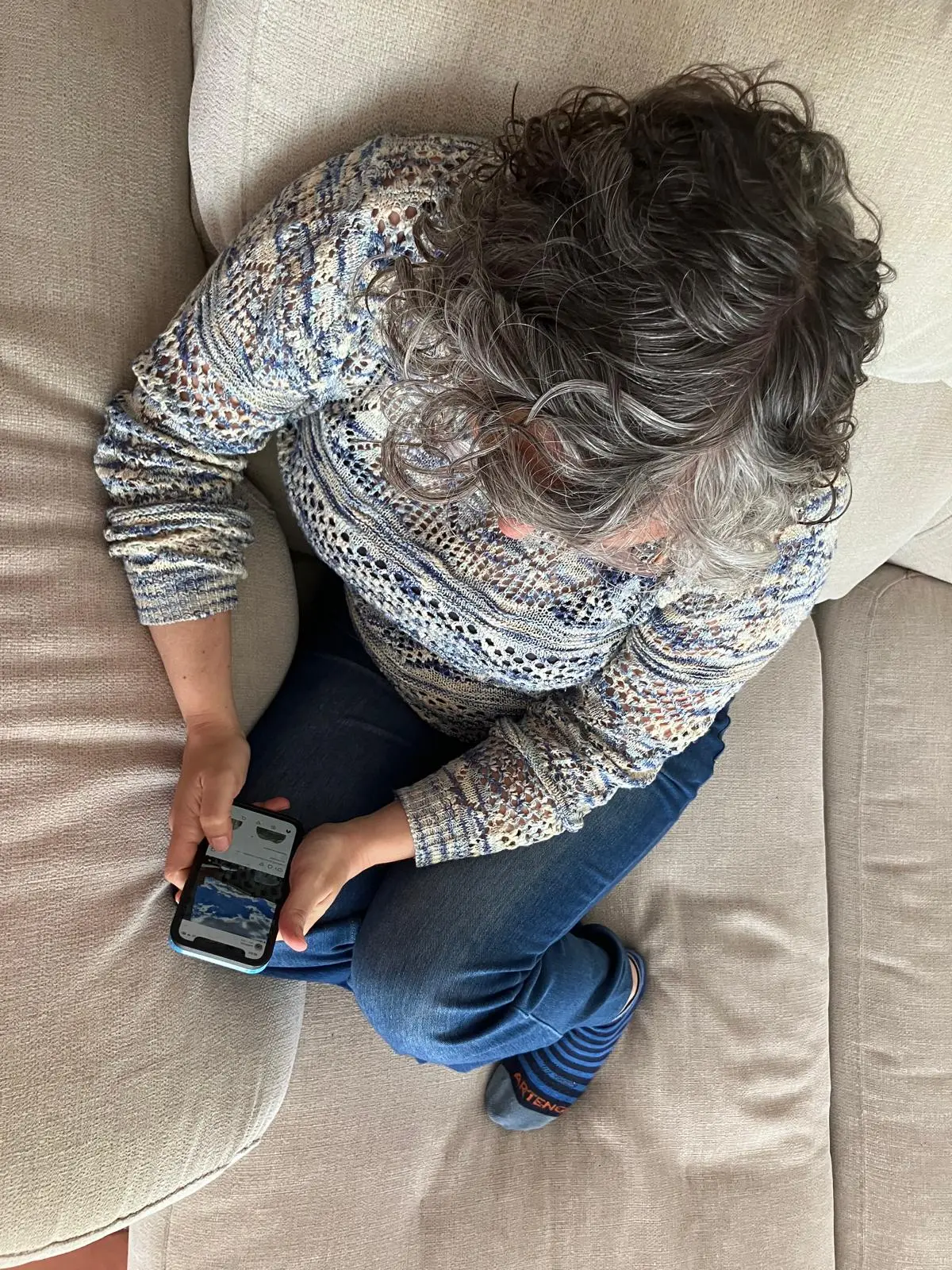 Persona mirant el mòbil al sofà