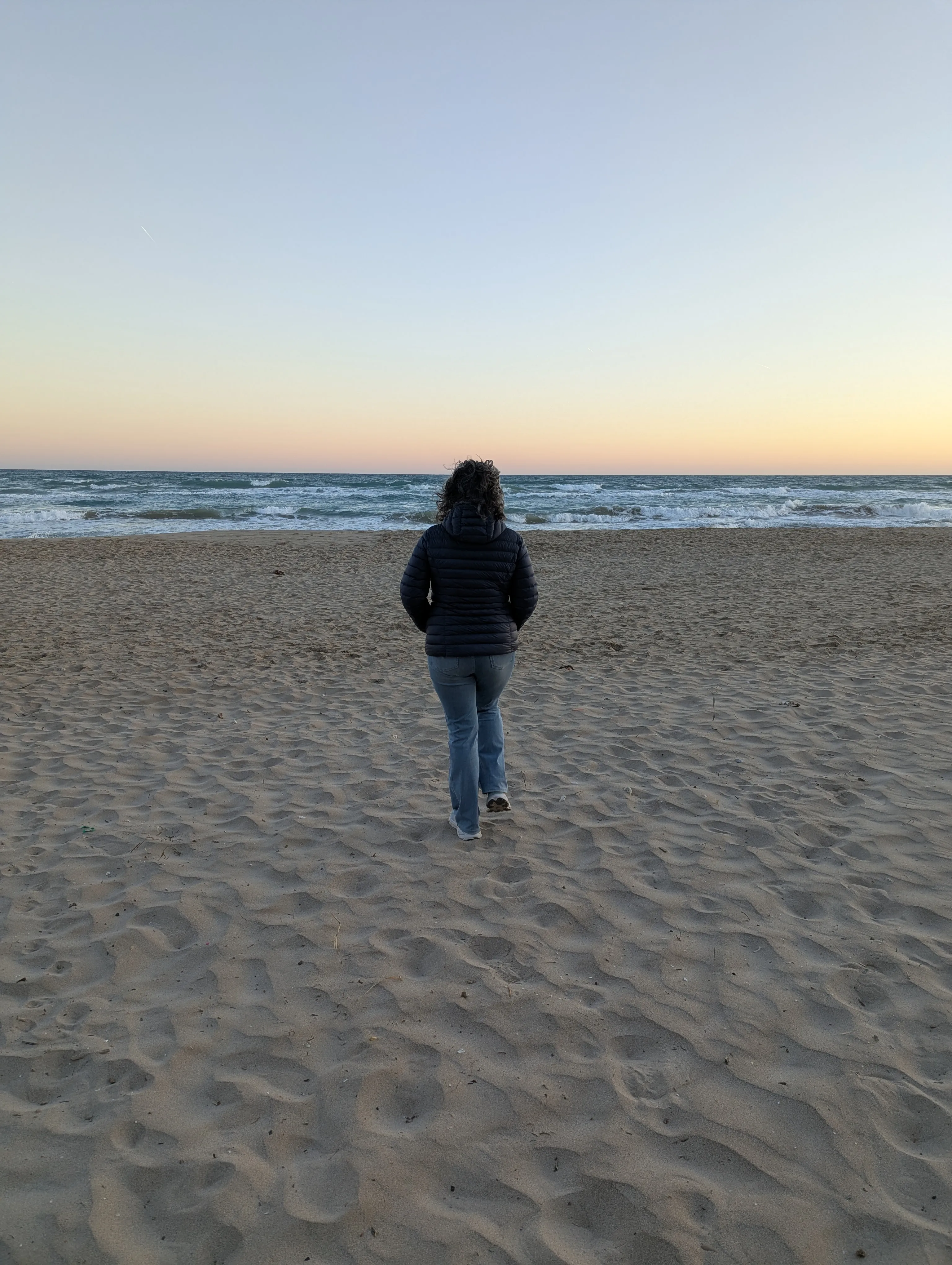 Persona andando sola por la playa por la tarde