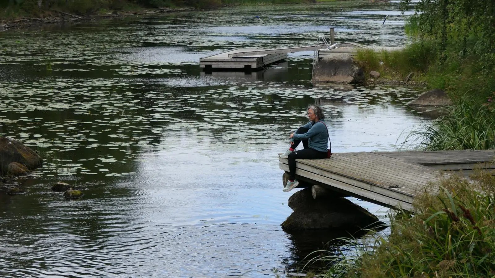 Persona asseguda al costat d'un llac en un moment de calma